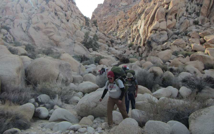 a group of people navigate over large rocks in Joshua Tree National Park